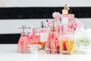 Bottles of perfume with flowers on light background